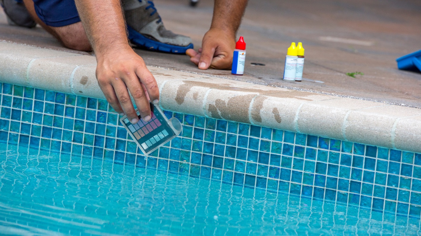 Pool professional testing water chemistry at the tile line